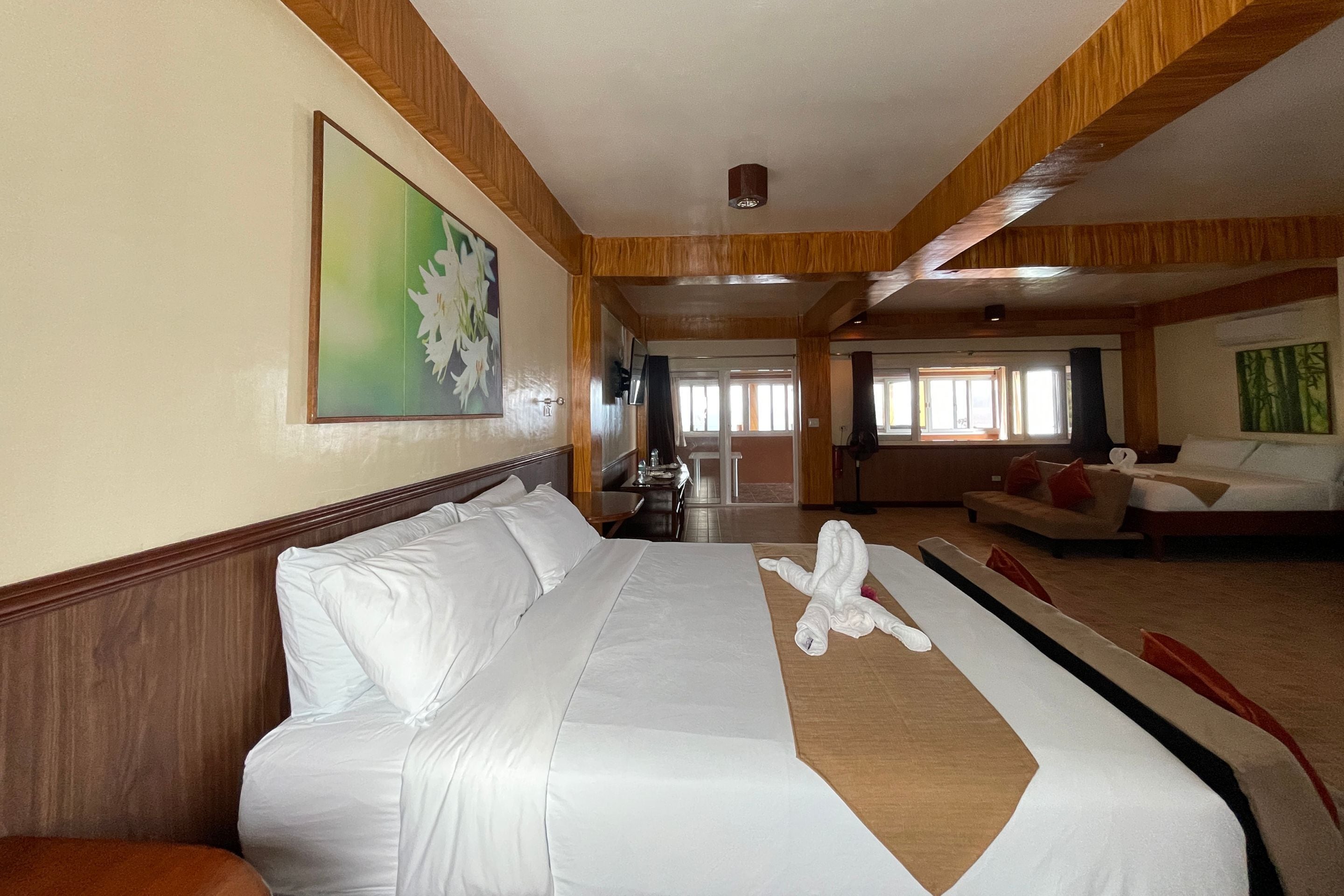 A hotel room with a large bed, a sofa, and a dining area.