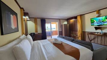 A hotel room with a large bed, a TV, and a view of the outdoors.