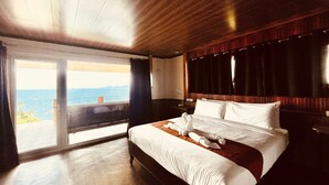 Un dormitorio con una cama grande, techo de madera y vistas al mar a través de una puerta corrediza.