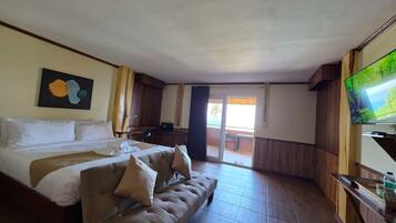 A hotel room with a bed, a sofa, a TV, and a sliding door to the outside.