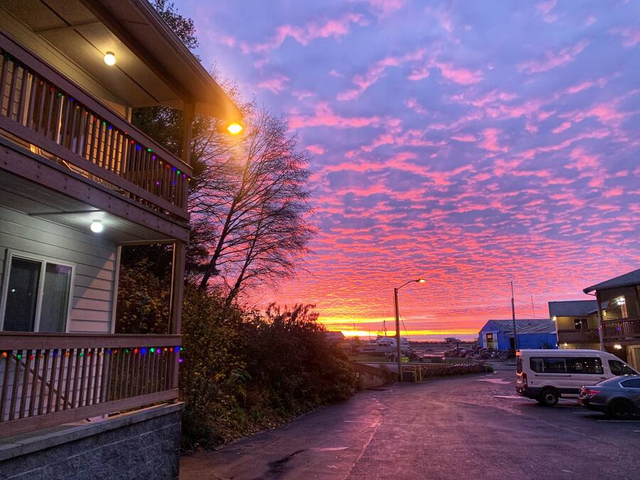 A residential street with a sunset, a wooden deck, and a parked van.