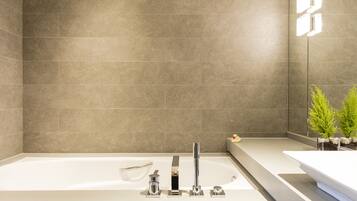 Un baño moderno con una bañera grande, un tocador elegante y una pequeña planta.