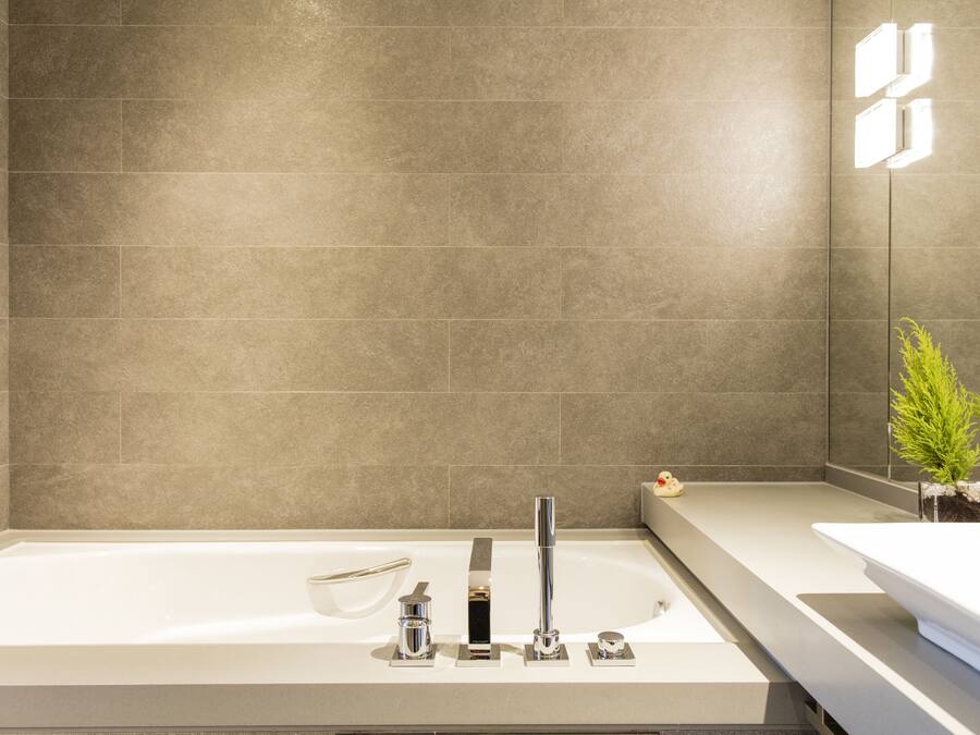 Un baño moderno con una bañera grande, un tocador elegante y una pequeña planta.