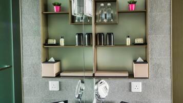 Uma casa de banho moderna com um espelho grande, duas bacias e uma toucador com bancada. Há prateleiras sobre o espelho com produtos de higiene e objetos decorativos.