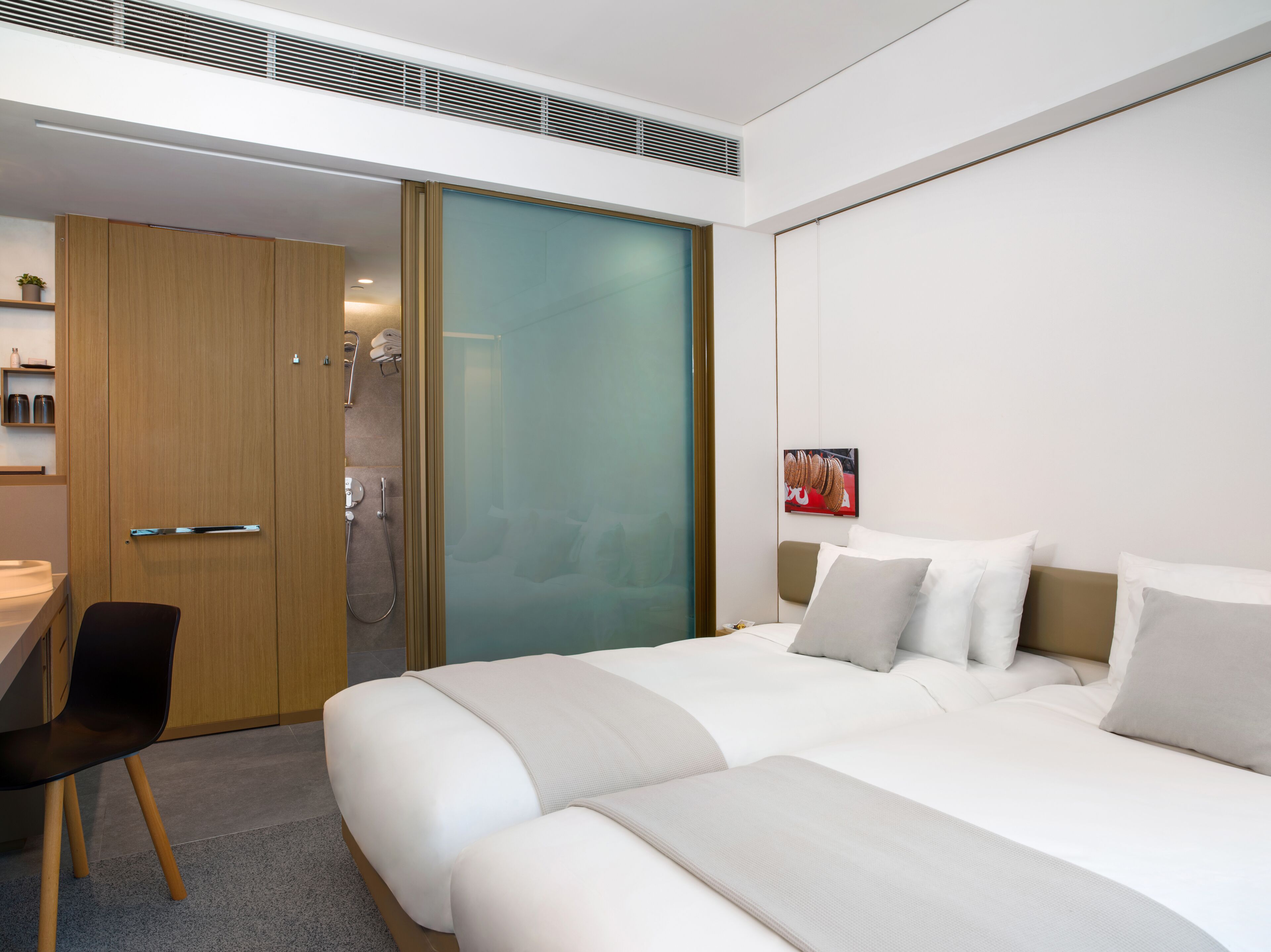 A modern hotel room with a large bed, a desk, and a shower area.