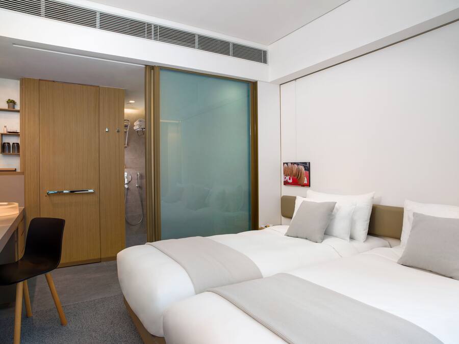 A modern hotel room with a large bed, a desk, and a shower area.