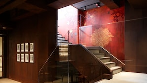 Un interior moderno con una escalera, paneles de madera y cuadros enmarcados.