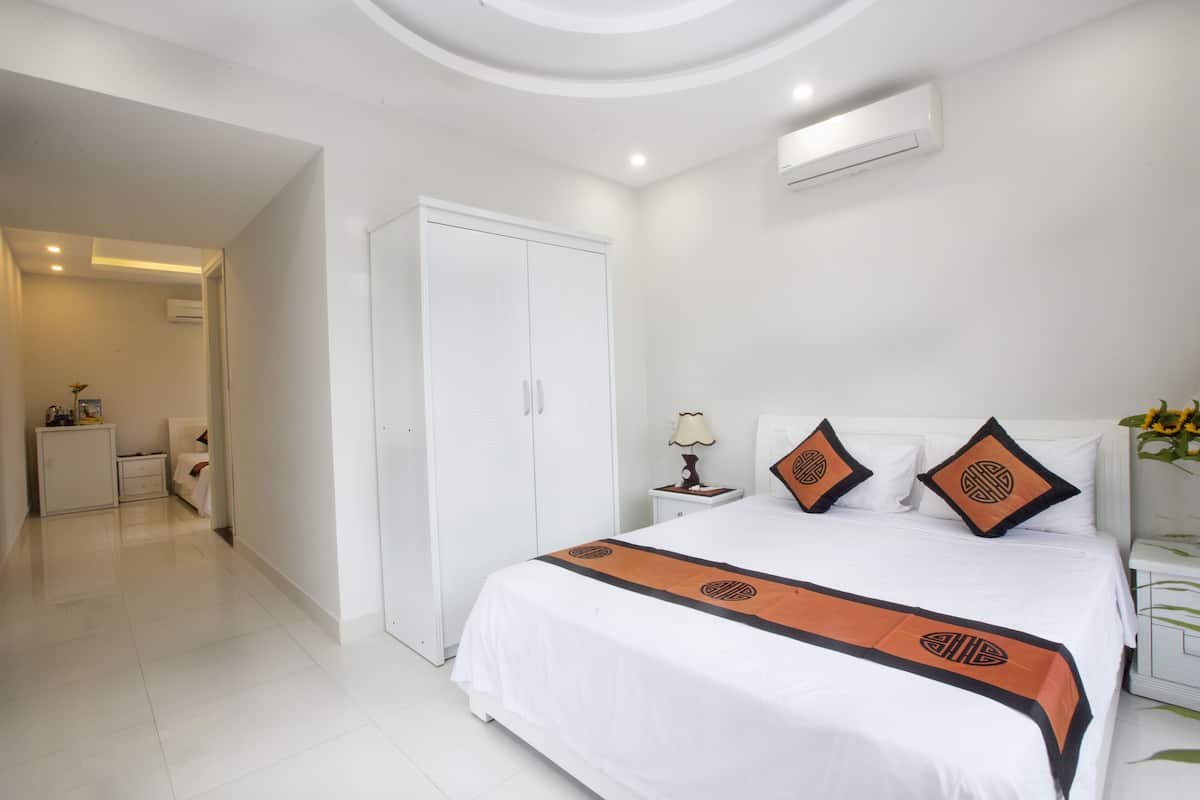 Une chambre d’hôtel comprenant un lit, une armoire, une table de chevet et une petite table avec une lampe.