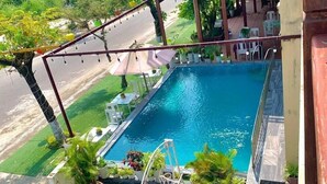 A rooftop pool with a view of the surrounding greenery and a street.