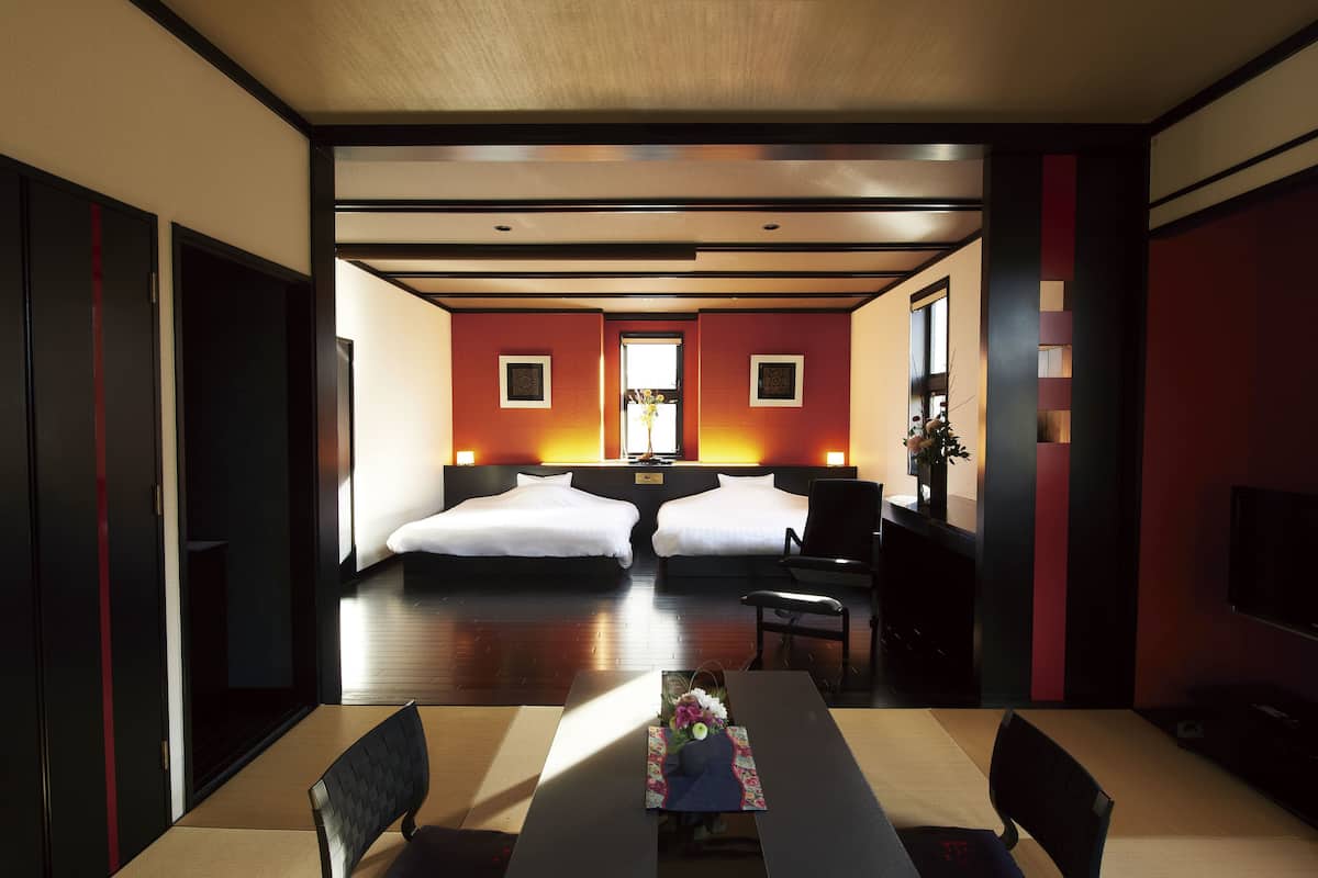 Ein Hotelzimmer mit zwei Betten, einem Esstisch und einem Fernseher.