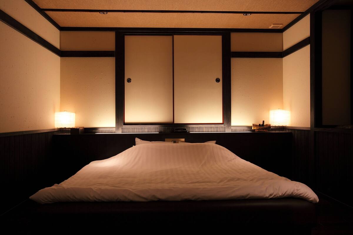 Ein Hotelzimmer mit einem großen Bett, zwei Nachttischlampen und einer traditionellen Schiebetür.