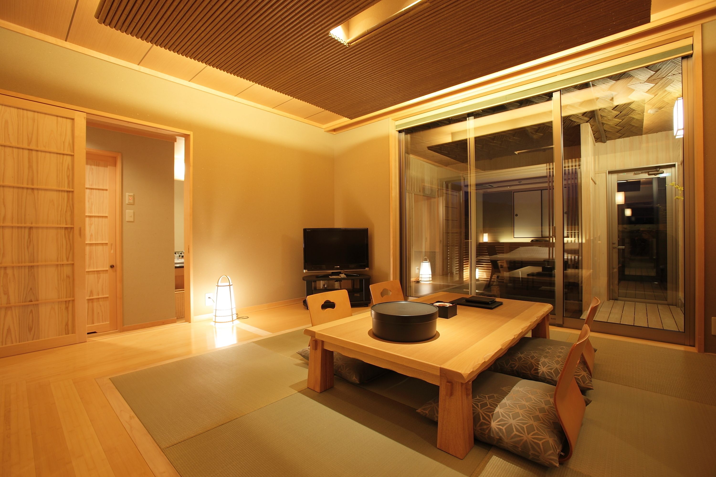 A traditional Japanese room with tatami flooring, a low wooden table, and sliding glass doors leading to a balcony.