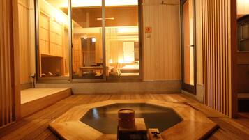 Un onsen japonès tradicional amb terres de fusta i una font termal central.