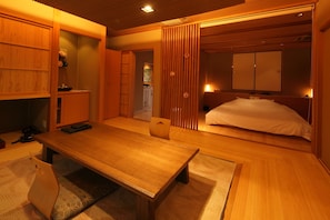 A traditional Japanese-style room with tatami flooring, a low wooden table, and a bed with a wooden headboard. - Bettei Soan (Minamiaso)