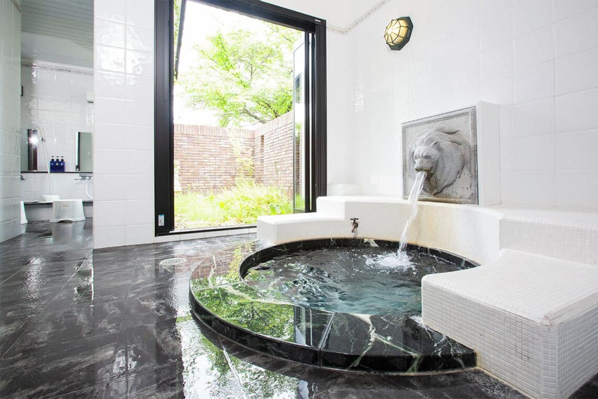 Ein modernes Badezimmer mit großem Fenster, Marmorwaschbecken und einer kleinen Fontäne.
