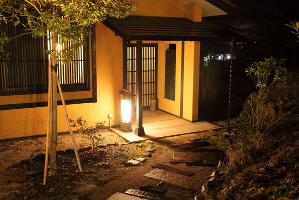 A traditional Japanese-style entrance with a wooden gate, a stone pathway, and a small tree. - Bettei Soan (Minamiaso)