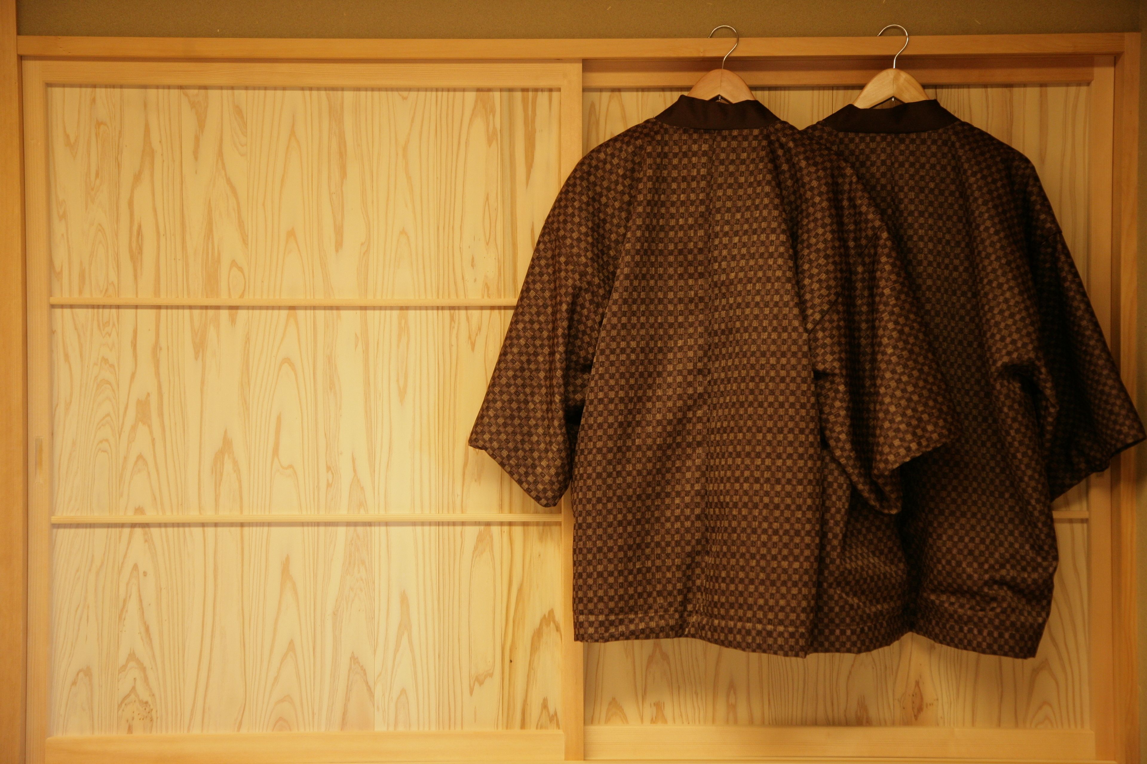Une armoire en bois avec deux cintres sur lesquels sont suspendus des vêtements à motifs.