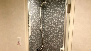 A shower with a tiled wall and a handheld showerhead. - HOTEL LiVEMAX BUDGET Kawasaki Daishi (Kawasaki)