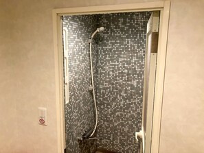 Ducha con pared de azulejos y cabezal de ducha de mano.