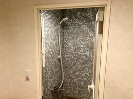 Ducha con pared de azulejos y cabezal de ducha de mano.