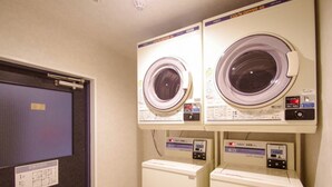 A laundry room with two front-loading washing machines and two stacked dryers. - HOTEL LiVEMAX BUDGET Kawasaki Daishi (Kawasaki)