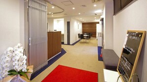 A hotel reception area with a reception desk, a seating area, and a red carpet. - HOTEL LiVEMAX BUDGET Kawasaki Daishi (Kawasaki)