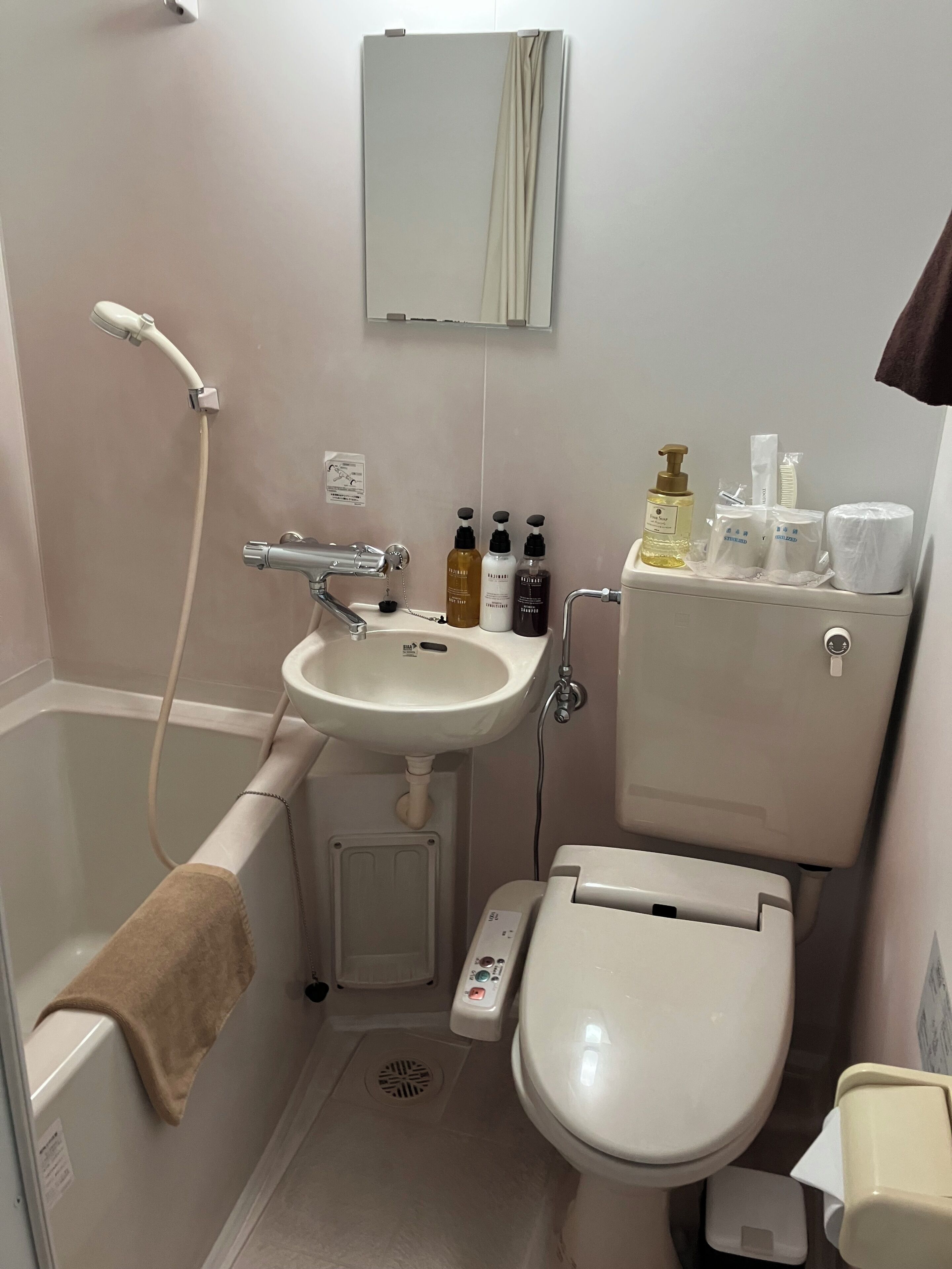 Un baño con bañera, lavamanos, inodoro y distintos artículos de aseo.