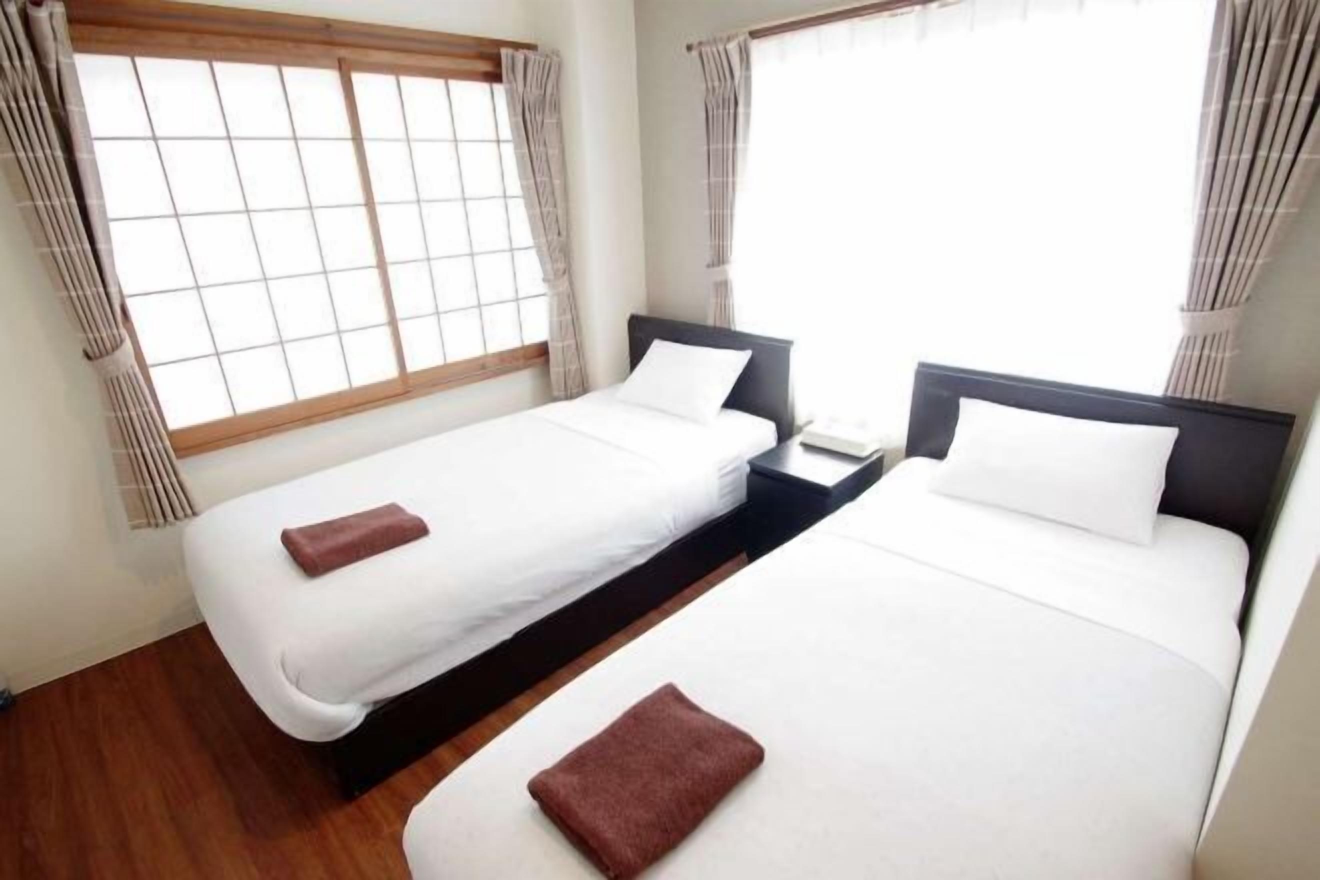 Habitación doble con dos camas, una ventana y cortinas.
