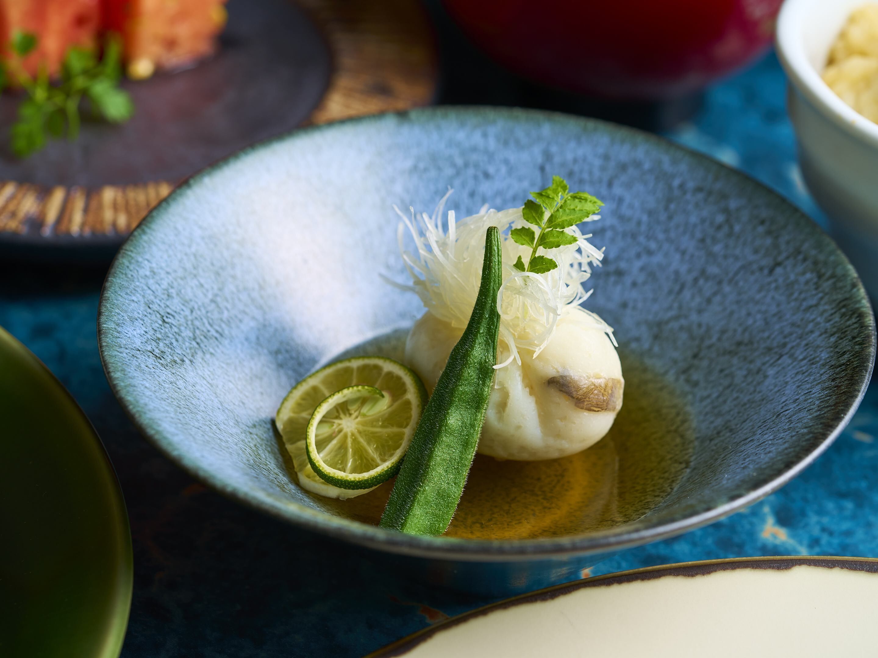 A bowl of food with a lime slice and green vegetable garnish.