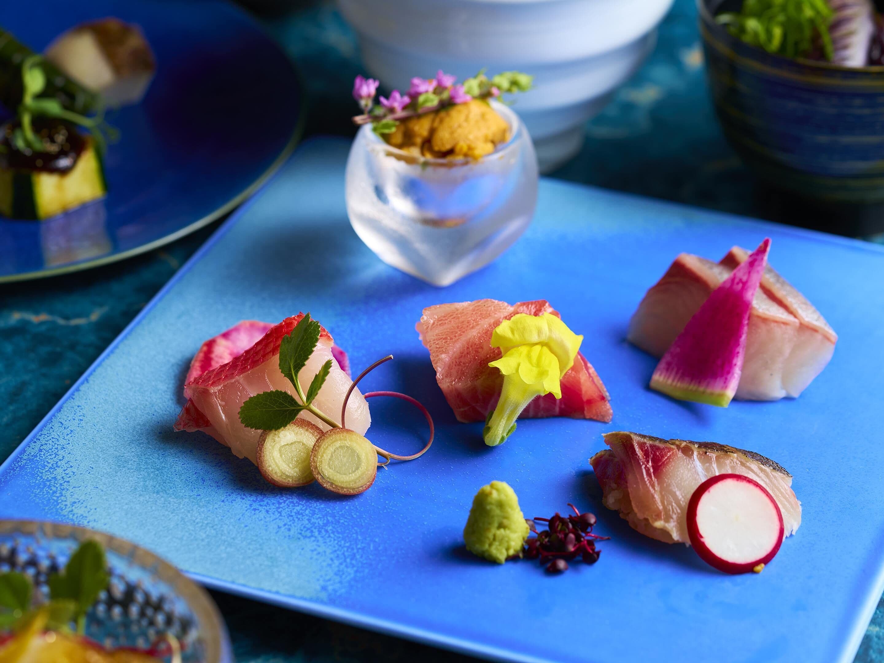 A blue plate with various food items, including fish and garnishes.