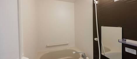 Un baño moderno con bañera, ducha y espejo.