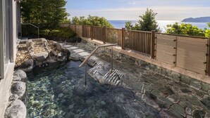 A clear pool with a wooden deck and stone steps leading to it, surrounded by a wooden fence and greenery. - Hotel New Akao (Atami)