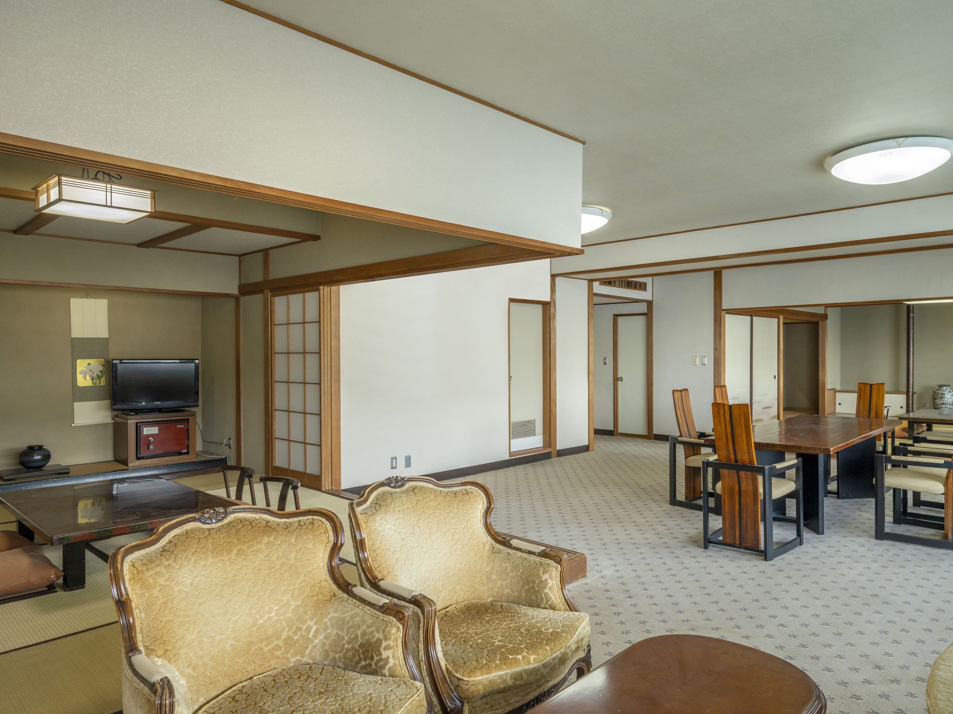 Uma sala de estar tradicional japonesa com tatames, uma mesa baixa e uma televisão sobre um móvel.