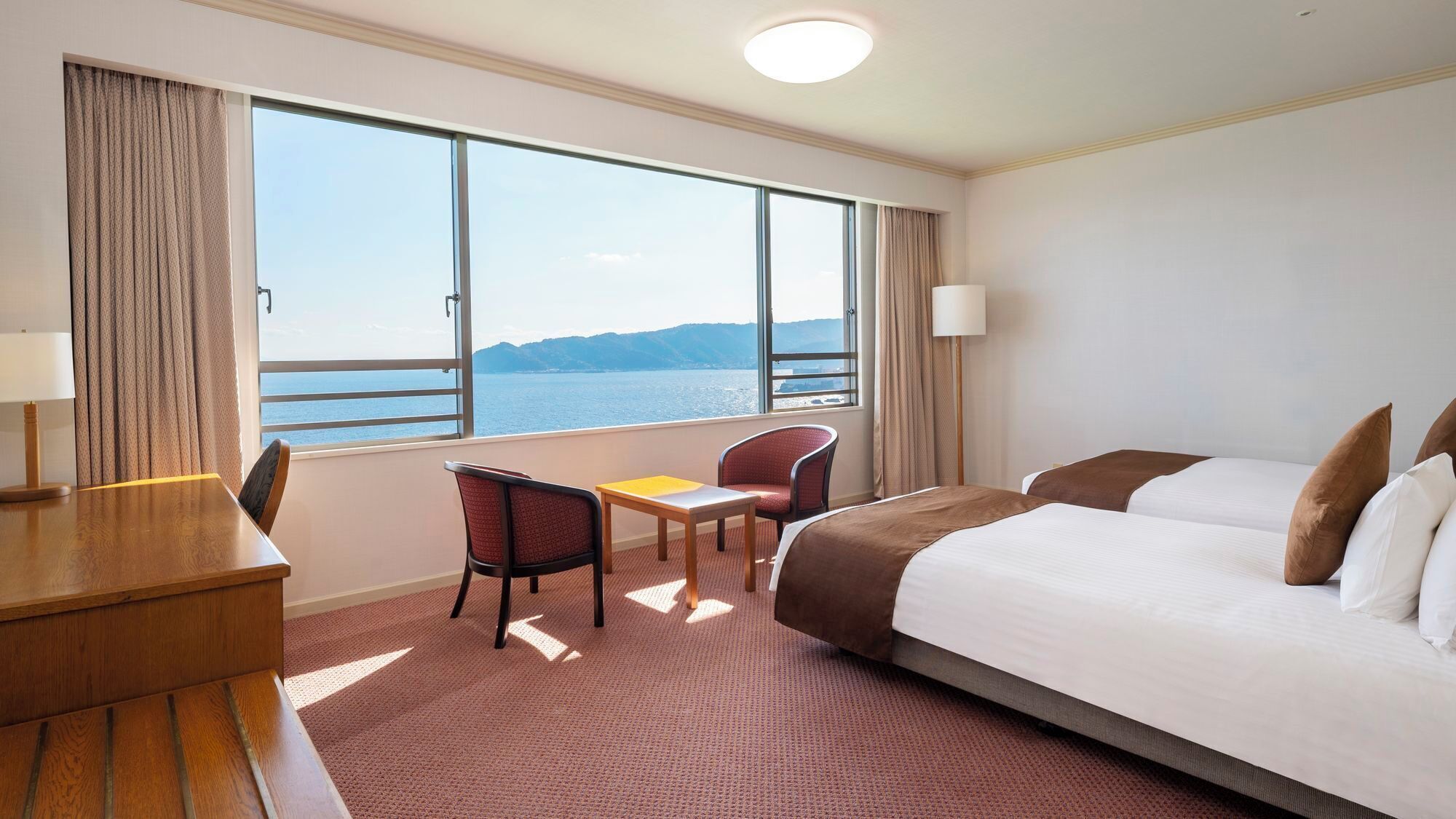 Habitación de hotel con cama, escritorio, silla y vista al mar.