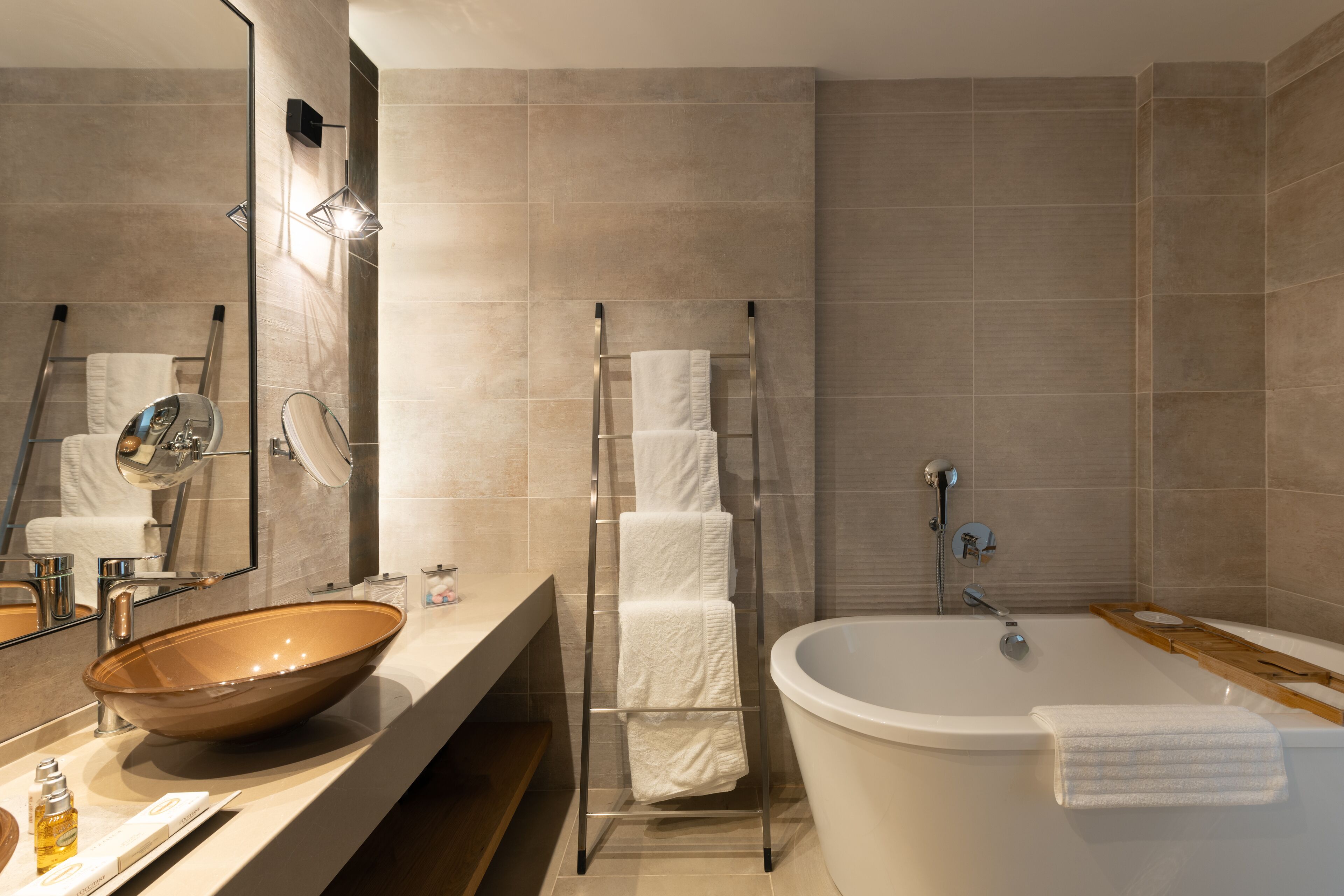 A modern bathroom with a large bathtub, a glass-topped vanity, and a large mirror.