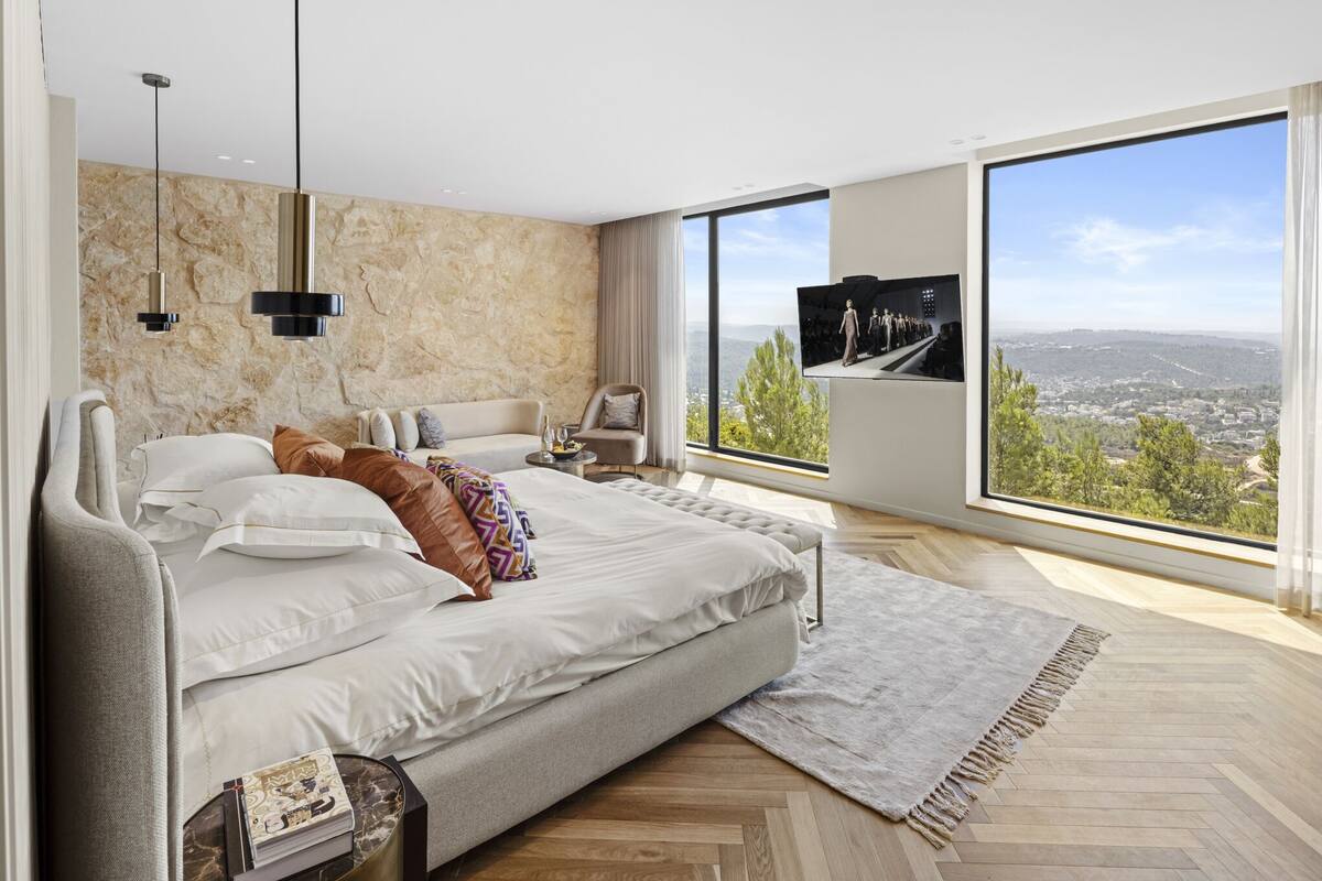 Une chambre moderne avec un grand lit, une télévision et une vue sur le paysage urbain.