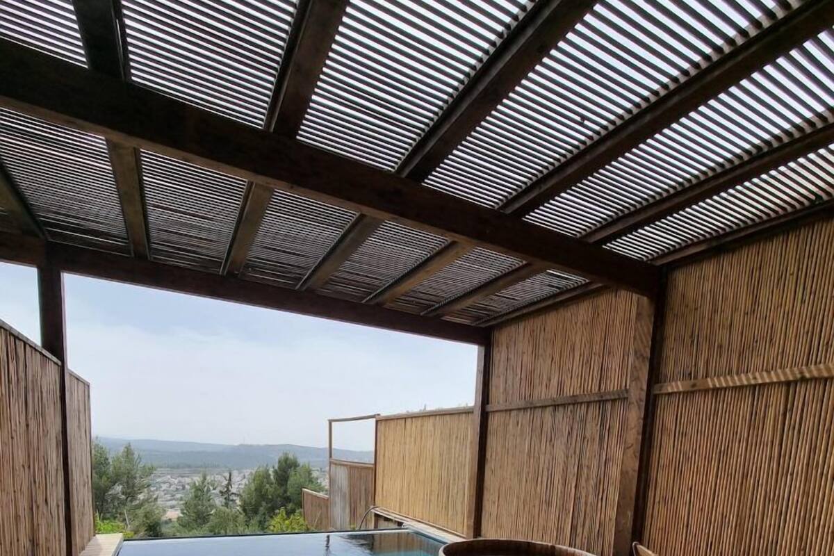 Une terrasse en bois avec un jacuzzi, des chaises longues et une piscine.