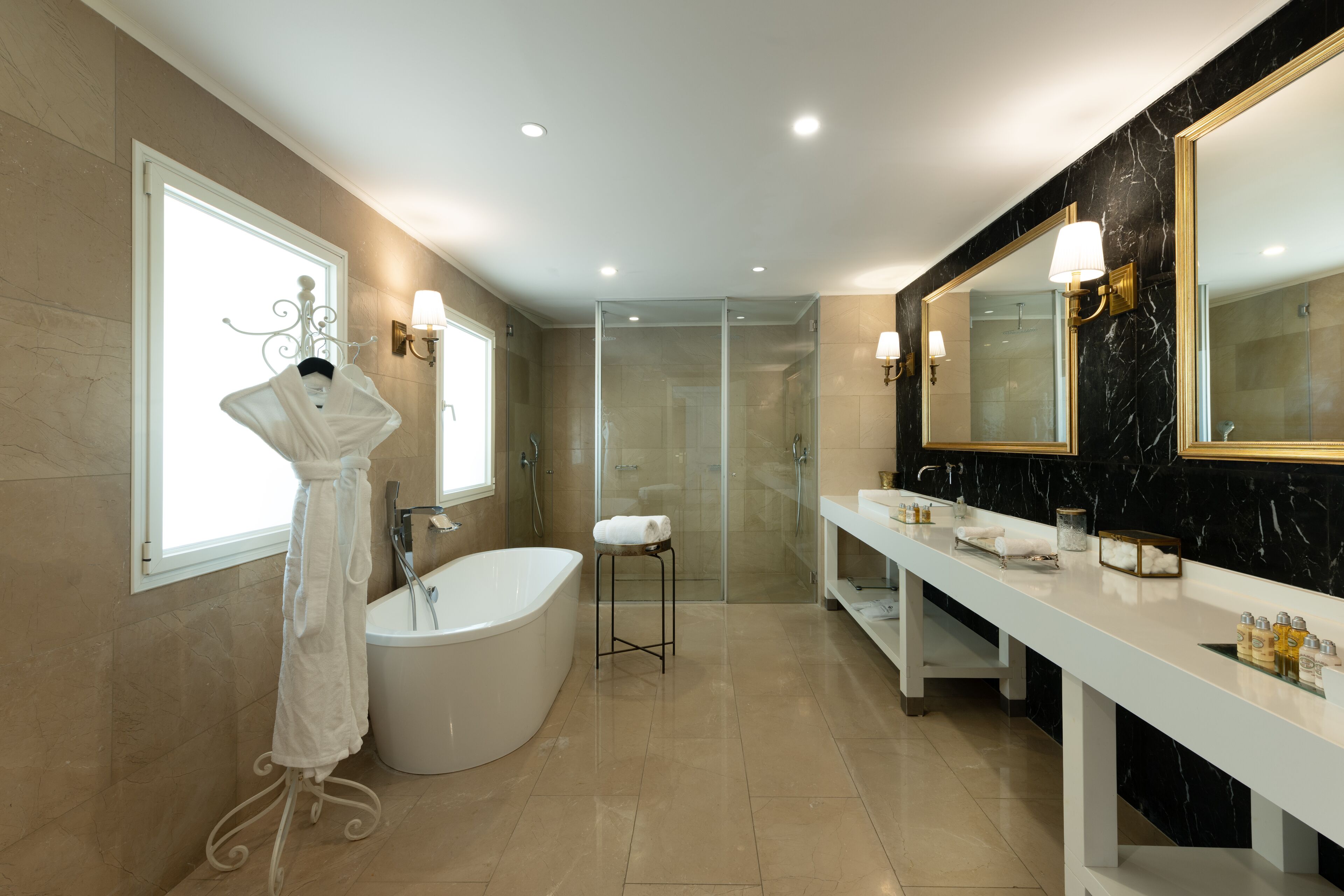 Un baño moderno con una bañera independiente, ducha con mampara de vidrio y tocador con un espejo grande.