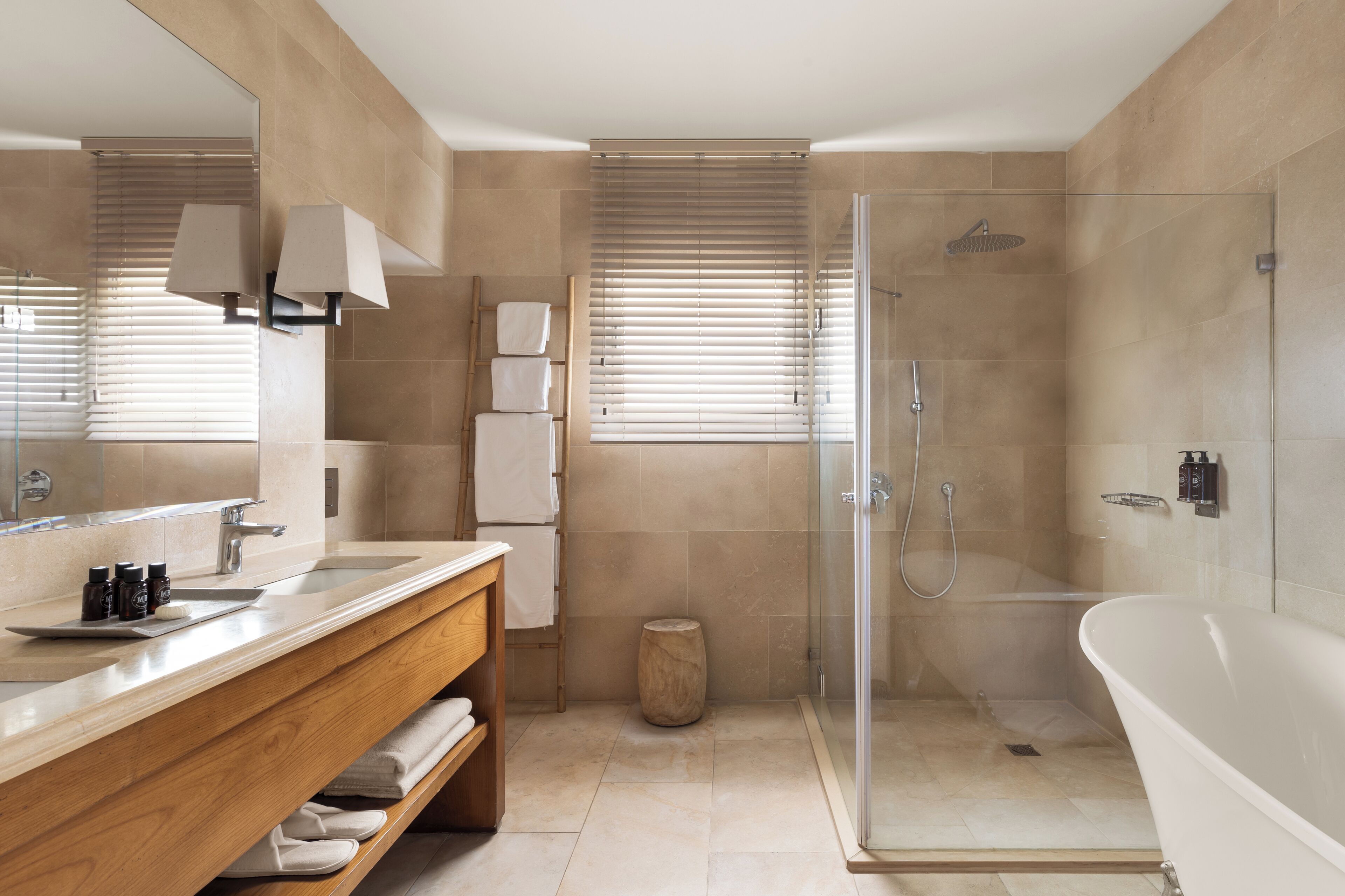 A modern bathroom with a large mirror, a wooden vanity, a glass shower enclosure, and a freestanding bathtub.