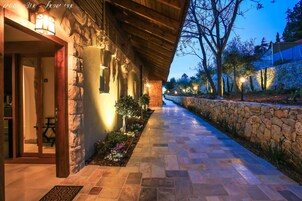 Un edificio de piedra con un corredor cubierto, asientos al aire libre y un muro de piedra.