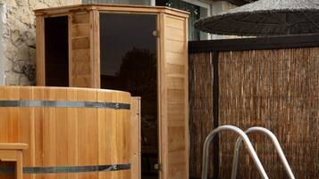 Un espace piscine doté d’un jacuzzi en bois, d’une terrasse en bois et d’une clôture en bambou.