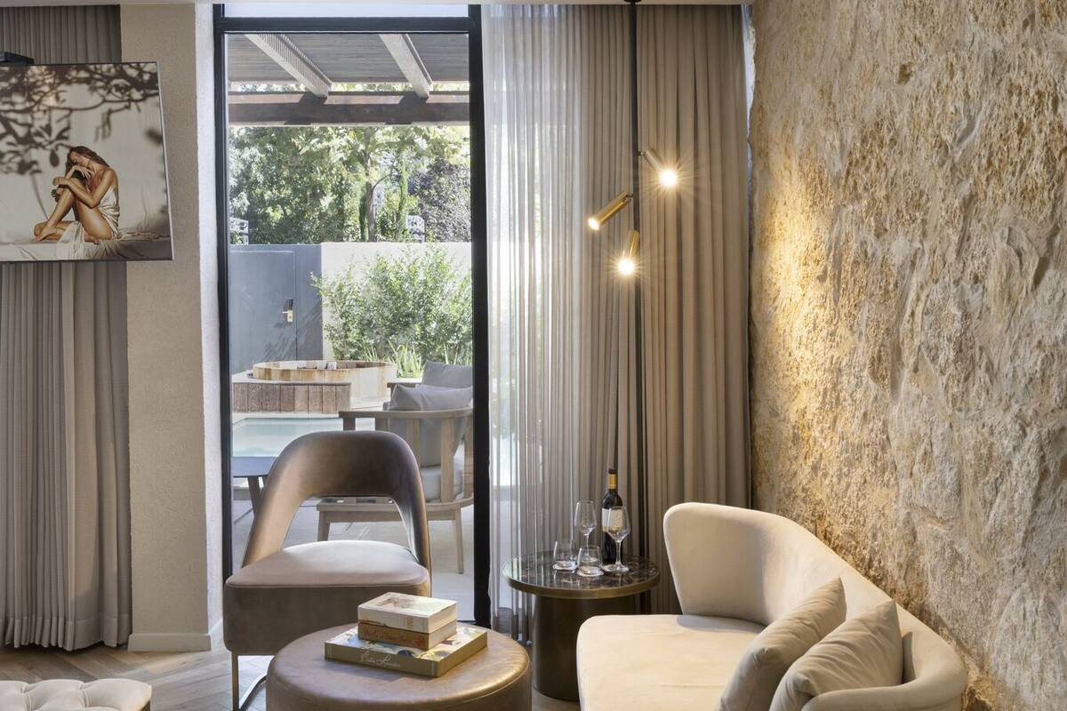 Une chambre moderne avec une grande fenêtre, un canapé, un pouf rond et un lit.