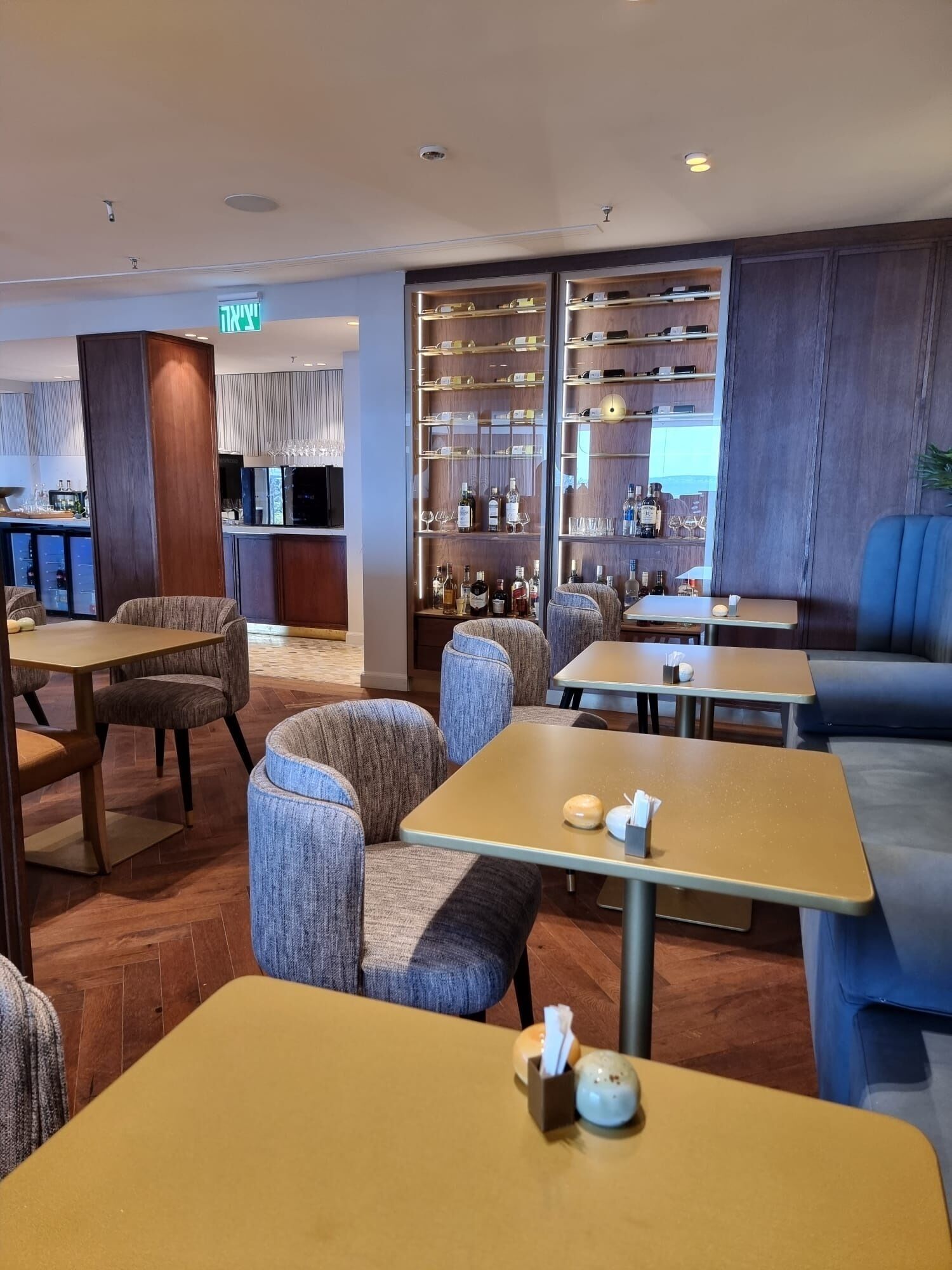 A modern restaurant with a bar area, seating arrangements, and a display of bottles.