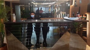 A reception area with a glass partition, a reception desk, and a reflection of the interior. - JRD Exotica (New Delhi)