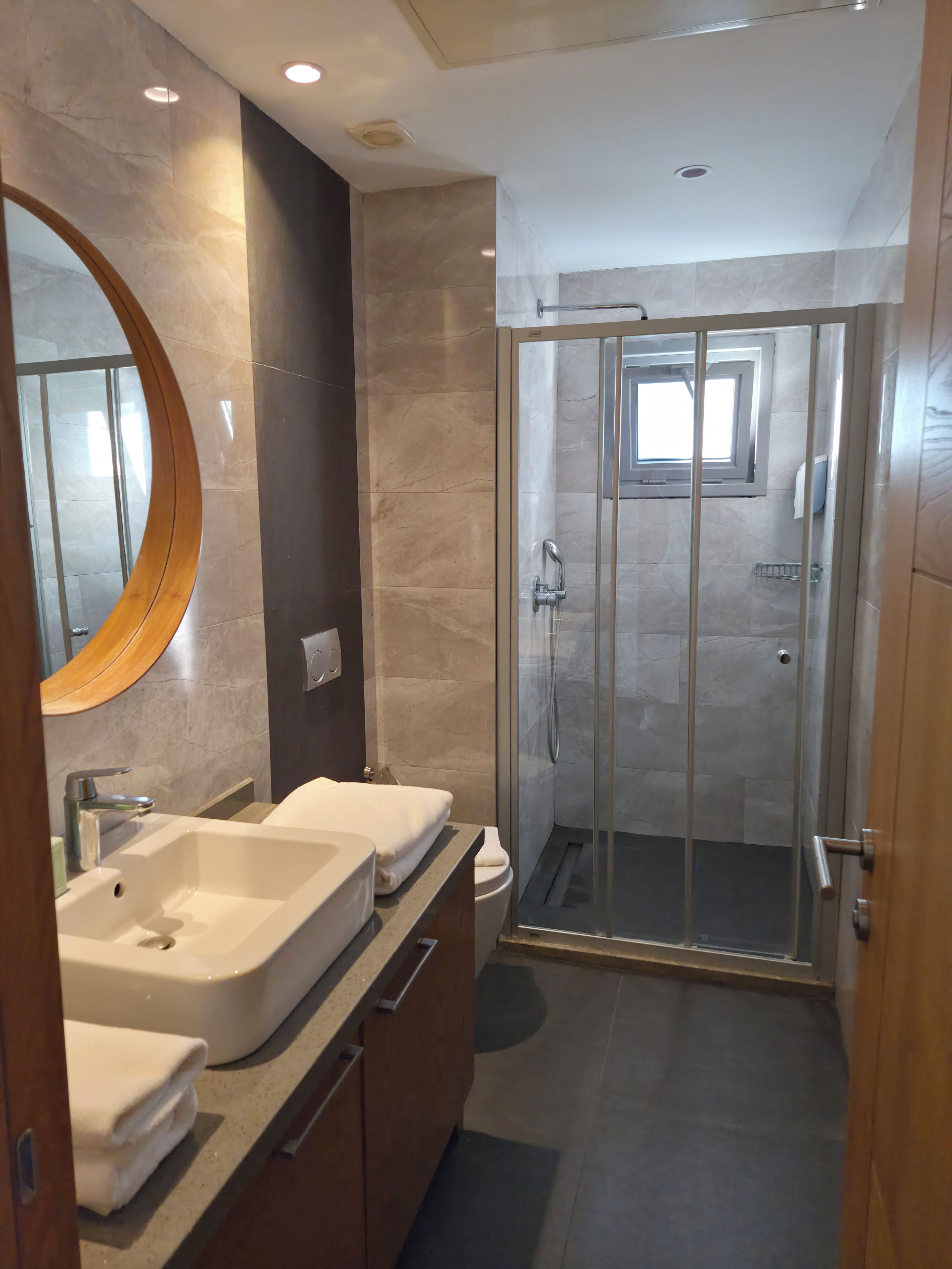 A modern bathroom with two sinks, a glass shower enclosure, and a large mirror.