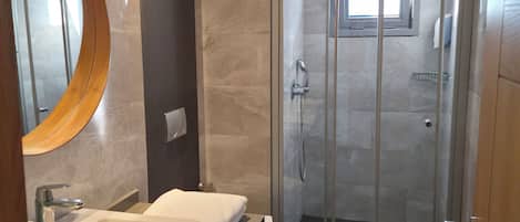 A modern bathroom with two sinks, a glass shower enclosure, and a large mirror.