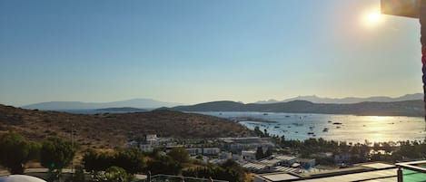 Un espace piscine doté de chaises longues et offrant une vue sur la mer et les montagnes.