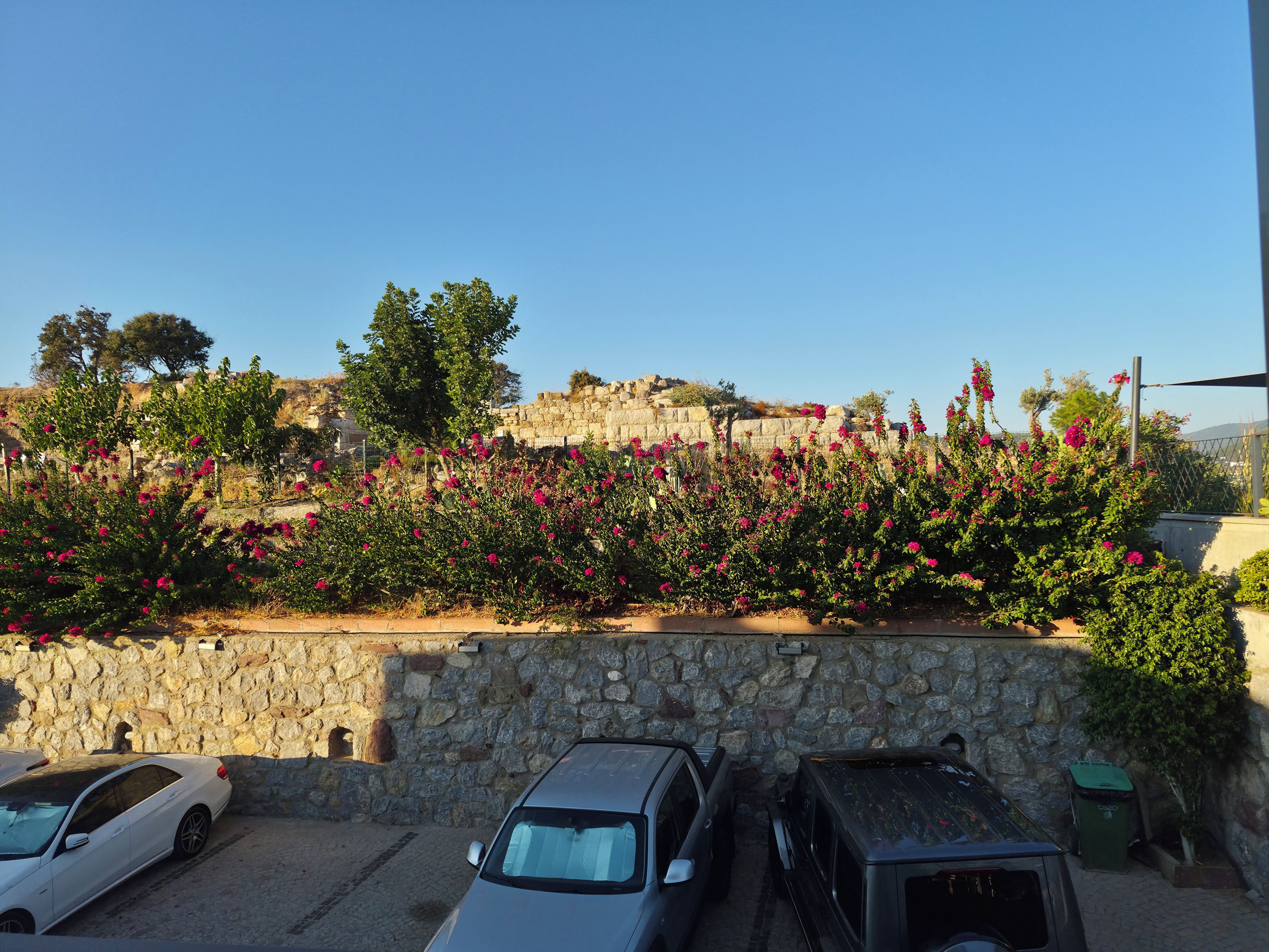 A parking area with stone walls and parked cars.