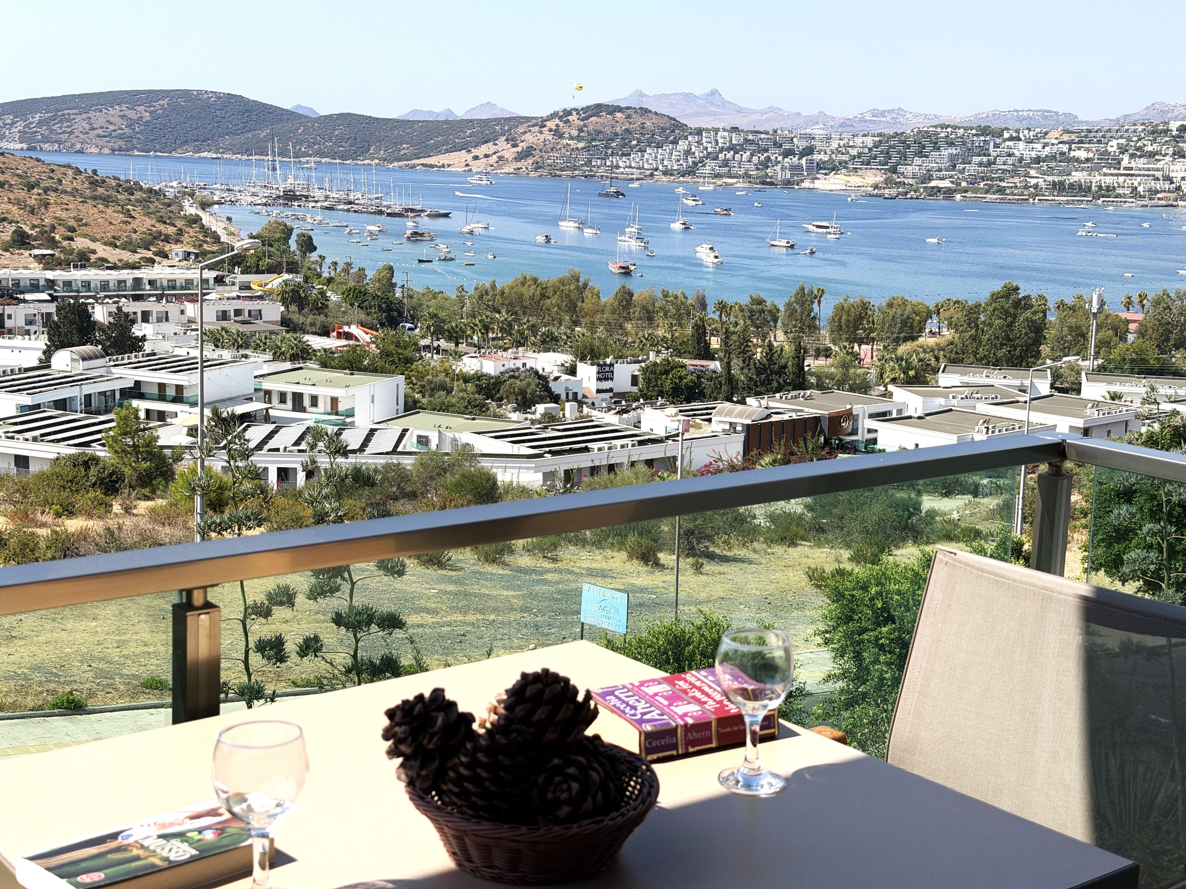 A balcony with a table, a wine glass, and a basket of pinecones.