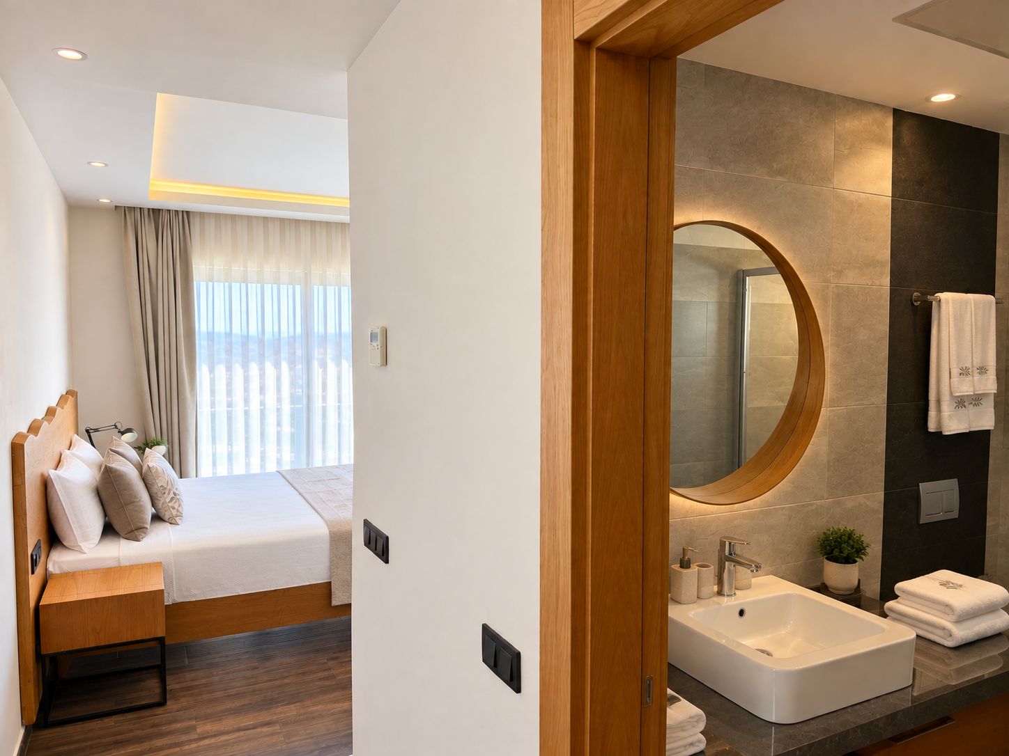 A modern hotel room with a bed, bedside table, and a large mirror above a sink.